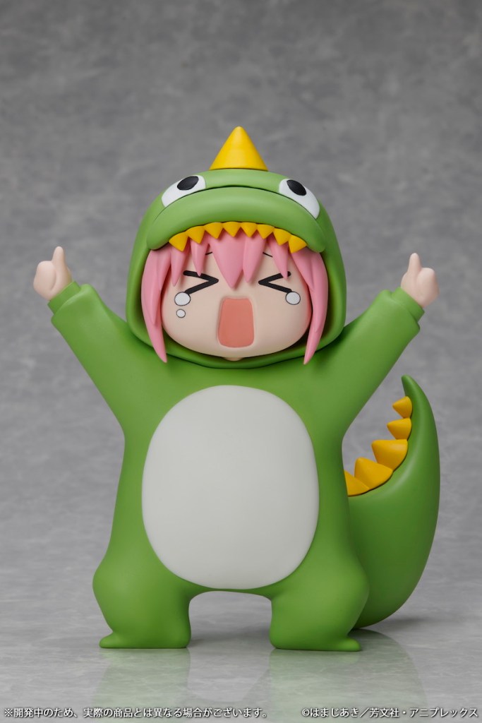 A cute Hitori Goto figure from Bocchi The Rock! wearing a green dinosaur costume, with pink hair and a cheerful expression, set against a neutral background.